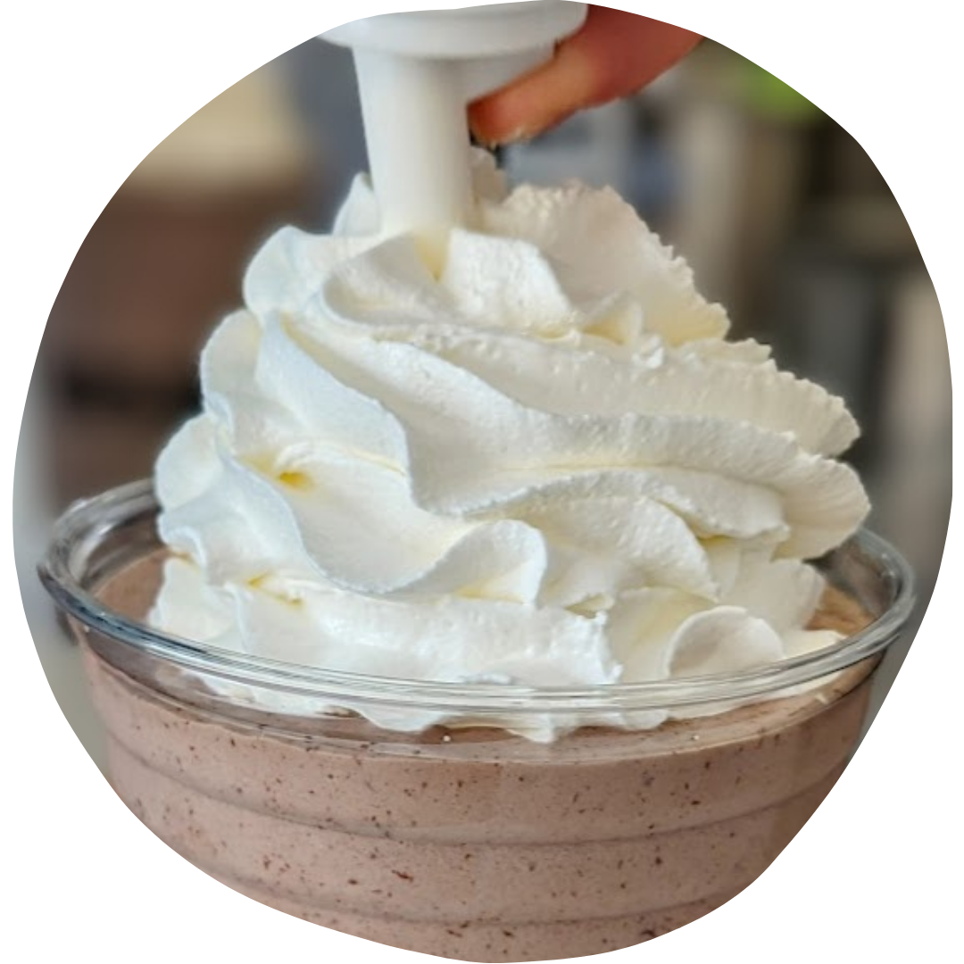 A delicious Eskimoo chocolate milkshake topped with cream. This image is placed in an uneven circular frame.